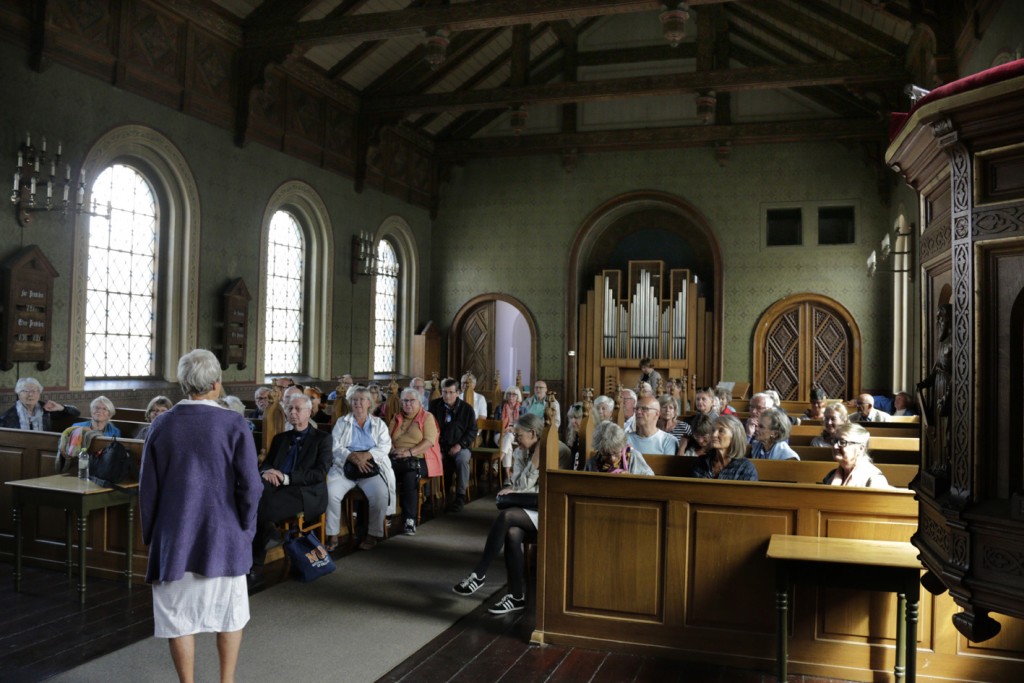 Speciallæge i psykiatri Karin Garde bød velkommen i hospitalets kirke med dens rigt udsmykkede træarbejder tegnet af arkitekten Gottlieb Bindesbøll. Foto: Finn Hillmose.